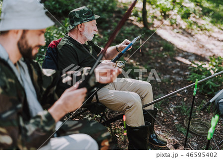 Elderly man putting bait on the hook while fishing Elderly man putting bait on the hook while fishing 46595402