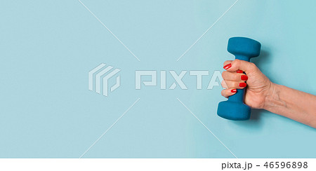 Female hand with blue dumbbell on blue. Sport.  46596898