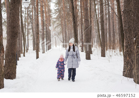 Happy family mother and child daughter having fun, playing at winter walk outdoors Happy family mother and child daughter having fun, playing at winter walk outdoors 46597152