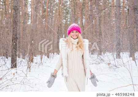 Fun, winter and people concept - Attractive young woman dressed in coat throwing snow. 46598248