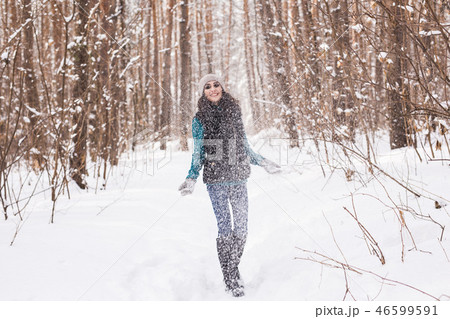 Happy young woman plays with a snow at snowy forest outdoor Happy young woman plays with a snow at snowy forest outdoor 46599591