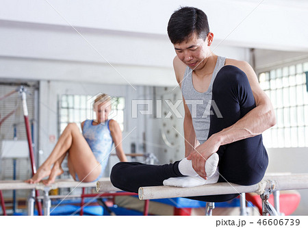 Acrobat exercising gymnastic action at chin-up bar in gym, woman on background 46606739