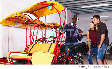 Pedicab driver negotiating with couple 46607204