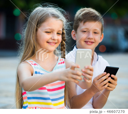 two kids with mobile phones outdoors. two kids with mobile phones outdoors. 46607270