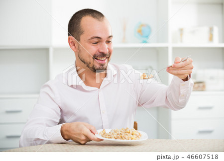 Positive young man eating porridge 46607518