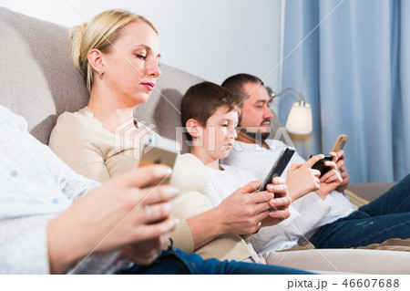 Parents and son using phones at home 46607688