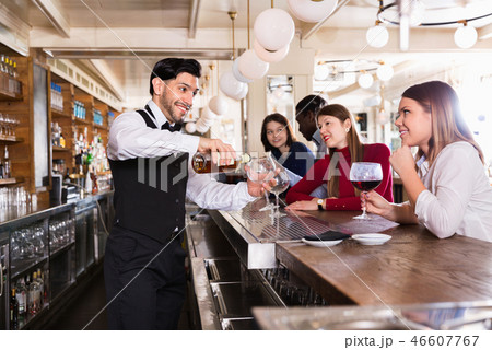 Portrait of barman and people who are standing near bar counter in luxurious restaurant Portrait of barman and people who are standing near bar counter in luxurious restaurant 46607767
