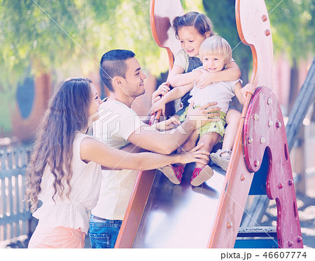 Smiling parents helping kids on slide Smiling parents helping kids on slide 46607774