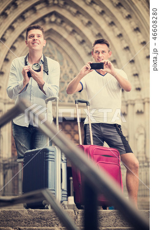 Smiling male couple of tourists taking photos at street 46608280