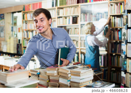 Young smiling male customer holding new book Young smiling male customer holding new book 46608628