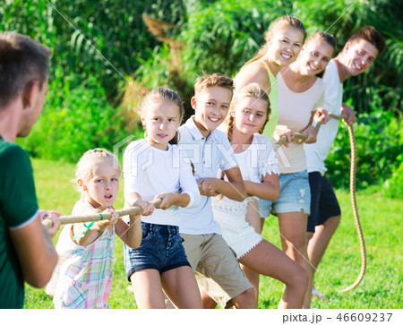 people with kids having fun outdoors pulling rope 46609237