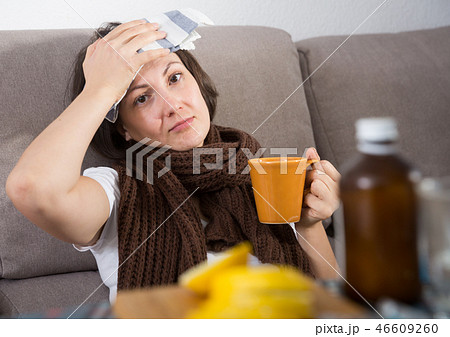 Sick woman with medicines lying on sofa Sick woman with medicines lying on sofa 46609260