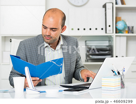 Cheerful man with folders and files at the laptop Cheerful man with folders and files at the laptop 46609299