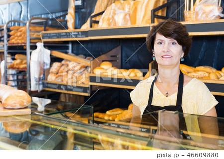 Woman baker with tasty baguettes and other bread products Woman baker with tasty baguettes and other bread products 46609880