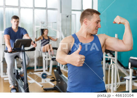 Guy posing among sports equipment at gym Guy posing among sports equipment at gym 46610104