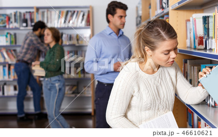 Female student choosing books on library shelves 46610621