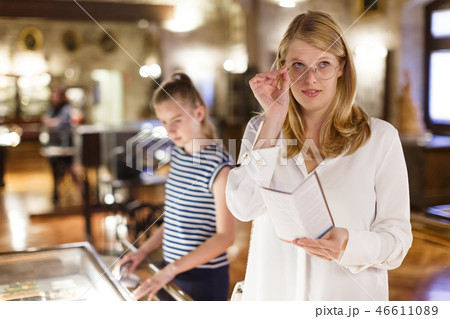 Female holding guidebook in museum of art, daughter on background 46611089