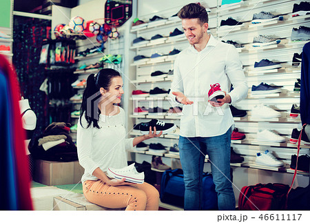 Positive seller demonstrating sneakers to female Positive seller demonstrating sneakers to female 46611117