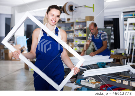 girl in workwear with window frame from pvc profile standing in workplace girl in workwear with window frame from pvc profile standing in workplace 46612778
