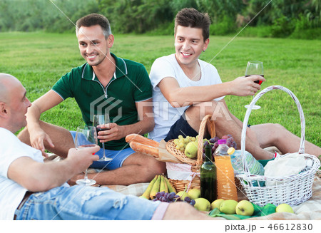 Three adult men enjoying picnic outdoors on summer day Three adult men enjoying picnic outdoors on summer day 46612830