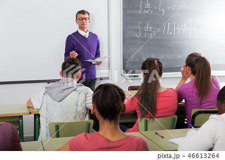 Teacher explaining the math near chalkboard . 46613264