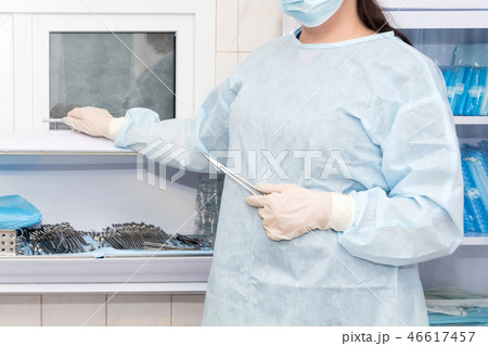 Doctor's hand holding vascular clamps in the operating room. Instruments for surgery in sterile box Doctor's hand holding vascular clamps in the operating room. Instruments for surgery in sterile box 46617457