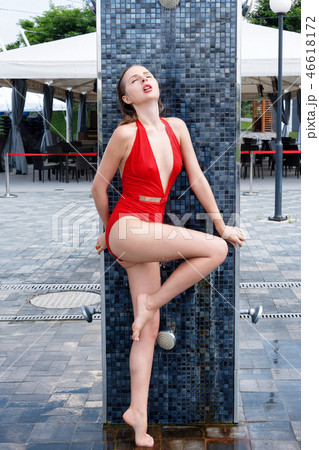 Beautiful young girl in red swimsuit near the pool takes a shower. sexy blonde girl with wet hair Beautiful young girl in red swimsuit near the pool takes a shower. sexy blonde girl with wet hair 46618172