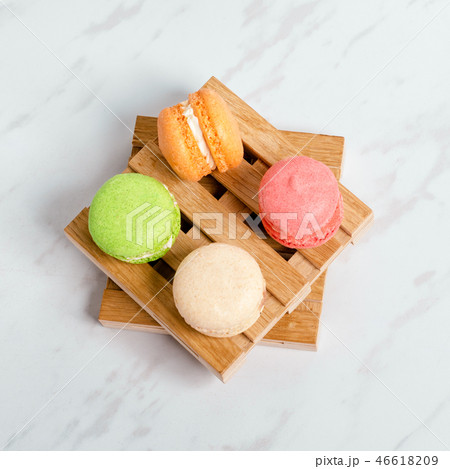Sweet and colourful macaroons served on little wooden pallets on a marble texture table. Traditional 46618209