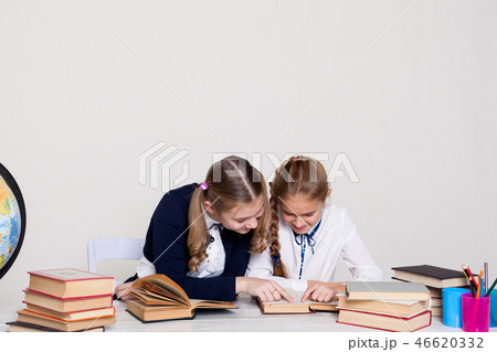 two schoolgirls girls in class at her desk with books notebooks 46620332