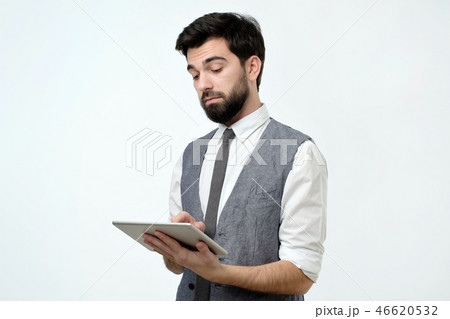 Pensive young handsome man using his digital tablet surfing in internet Pensive young handsome man using his digital tablet surfing in internet 46620532