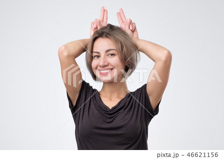 Young woman making bunny ears with hands Young woman making bunny ears with hands 46621156