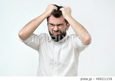 Enraged young businessman pulling his hair out for exasperation, having a burnout at work Enraged young businessman pulling his hair out for exasperation, having a burnout at work 46621158
