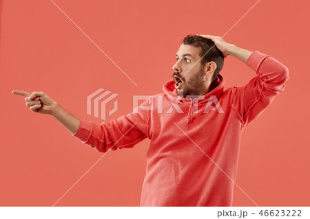 The young attractive man looking suprised isolated on coral The young attractive man looking suprised isolated on coral 46623222