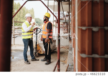 Portrait Of Happy Construction Site Supervisor Talking To Manual Worker 46623310