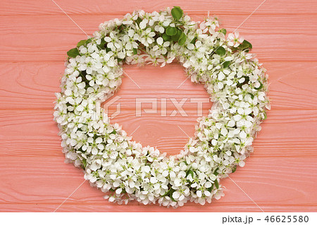 Round frame wreath made of spring flowers and leaves on coral wooden background. Flat lay. Top view. 46625580
