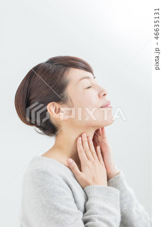 両手で首を触る女性の横顔の写真素材
