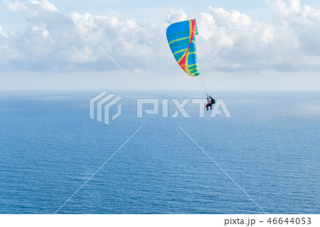 Flying a tandem paraglider over the sea with views of the horizon 46644053
