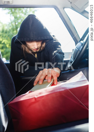 Burglar thief stealing smartphone and bag from car 46646015