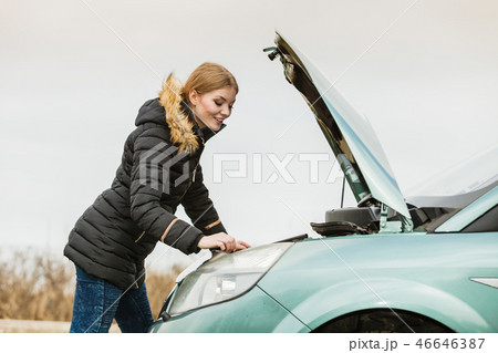 Blonde woman and broken down car on road 46646387