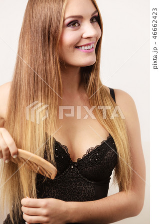 Woman combing her long hair with wooden comb Woman combing her long hair with wooden comb 46662423