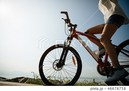 Hands free cycling woman riding bike on seaside Hands free cycling woman riding bike on seaside 46678758
