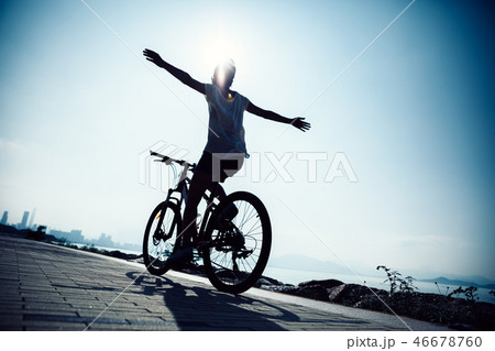 Hands free cycling woman riding bike on seaside 46678760