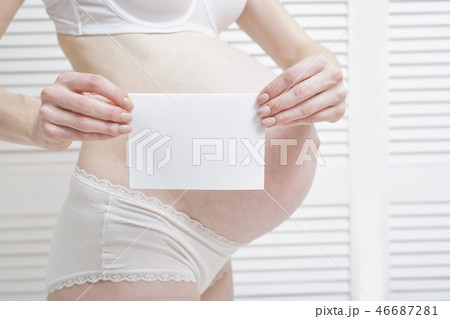 Pregnant woman is holding a white blank sheet Pregnant woman is holding a white blank sheet 46687281