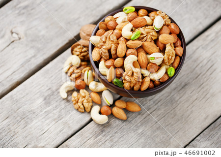 Wooden bowl with mixed nuts on a wooden gray background. Walnut, pistachios, almonds, hazelnuts and Wooden bowl with mixed nuts on a wooden gray background. Walnut, pistachios, almonds, hazelnuts and 46691002