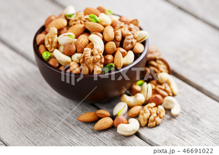 Wooden bowl with mixed nuts on a wooden gray background. Walnut, pistachios, almonds, hazelnuts and 46691022