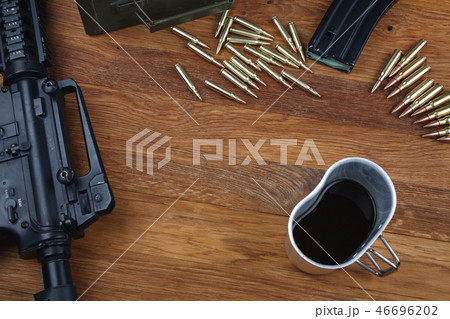 assault rifle and cup of coffee on wooden table 46696202
