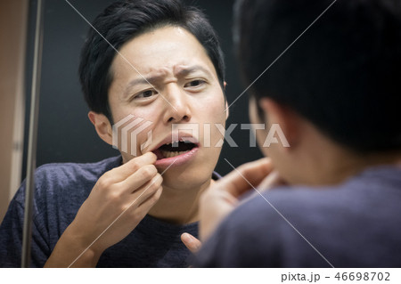 鏡を見る若い日本人男性 口内炎 歯周病 46698702