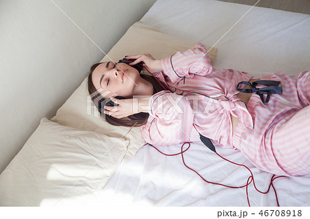 woman in pink Pajamas listening to music in headphones dancing on the bed woman in pink Pajamas listening to music in headphones dancing on the bed 46708918