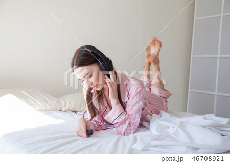 woman in pink Pajamas listening to music in headphones dancing on the bed woman in pink Pajamas listening to music in headphones dancing on the bed 46708921