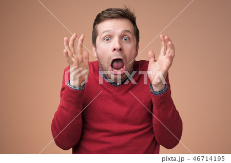 Man being shocked looking at camera with wide opened mouth and bugged eyes shouting with horror. 46714195
